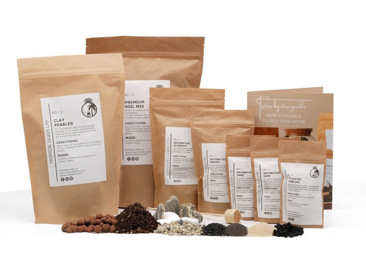 A collection of eco-friendly packaging featuring various materials for creating a DIY terrarium, including bags of clay pebbles, soil mix, and decorative stones. Instructions for assembling the terrarium are included on a printed guide.