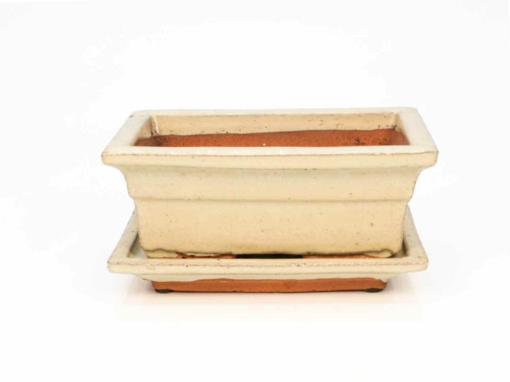 A rectangular decorative pot with a saucer, featuring a light beige exterior and a terracotta base. The pots sleek design.