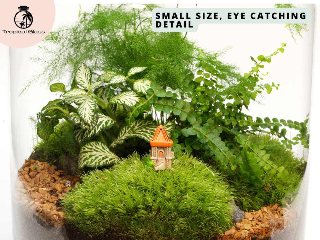 Mini castle tower figurine in a fairy garden style display with moss and stones