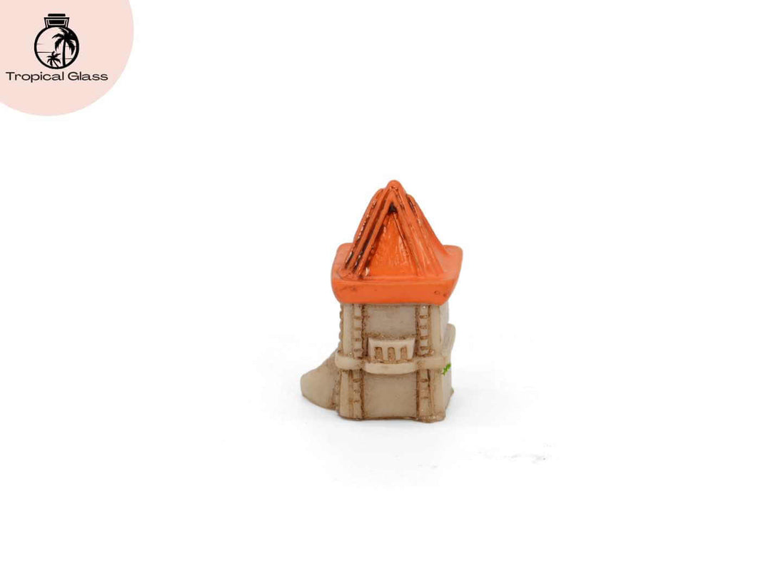 Side profile view of the mini castle tower figurine with orange roof and arched door detail