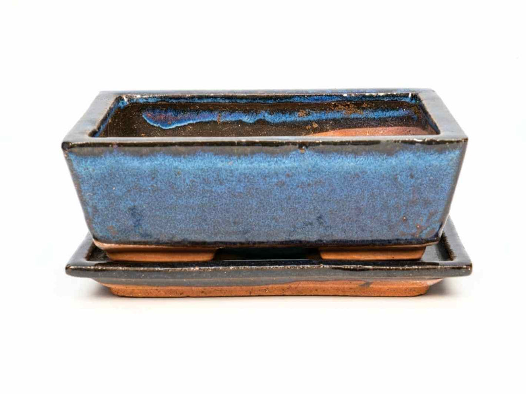 A rectangular ceramic decorative pot with a glossy dark blue finish, resting on a matching saucer. The pot features a sleek design.