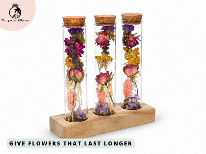 A wooden stand holds three glass test tubes filled with an assortment of dried flowers, displaying vibrant colors and varied textures. The cork tops add a rustic touch, making this arrangement a charming decorative piece.