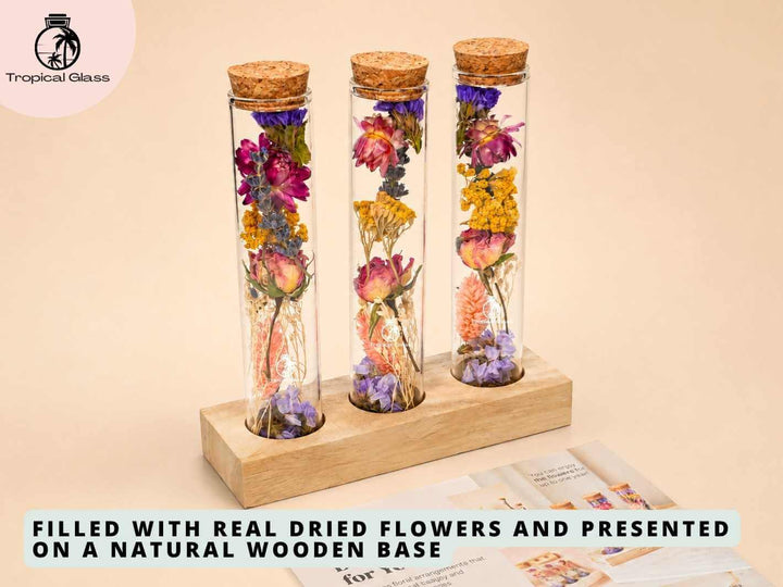 A rustic wooden stand holds three glass vials, each filled with a unique arrangement of real dried flowers in vibrant colors. The display showcases the beauty of nature, making it an ideal decorative piece or thoughtful gift.