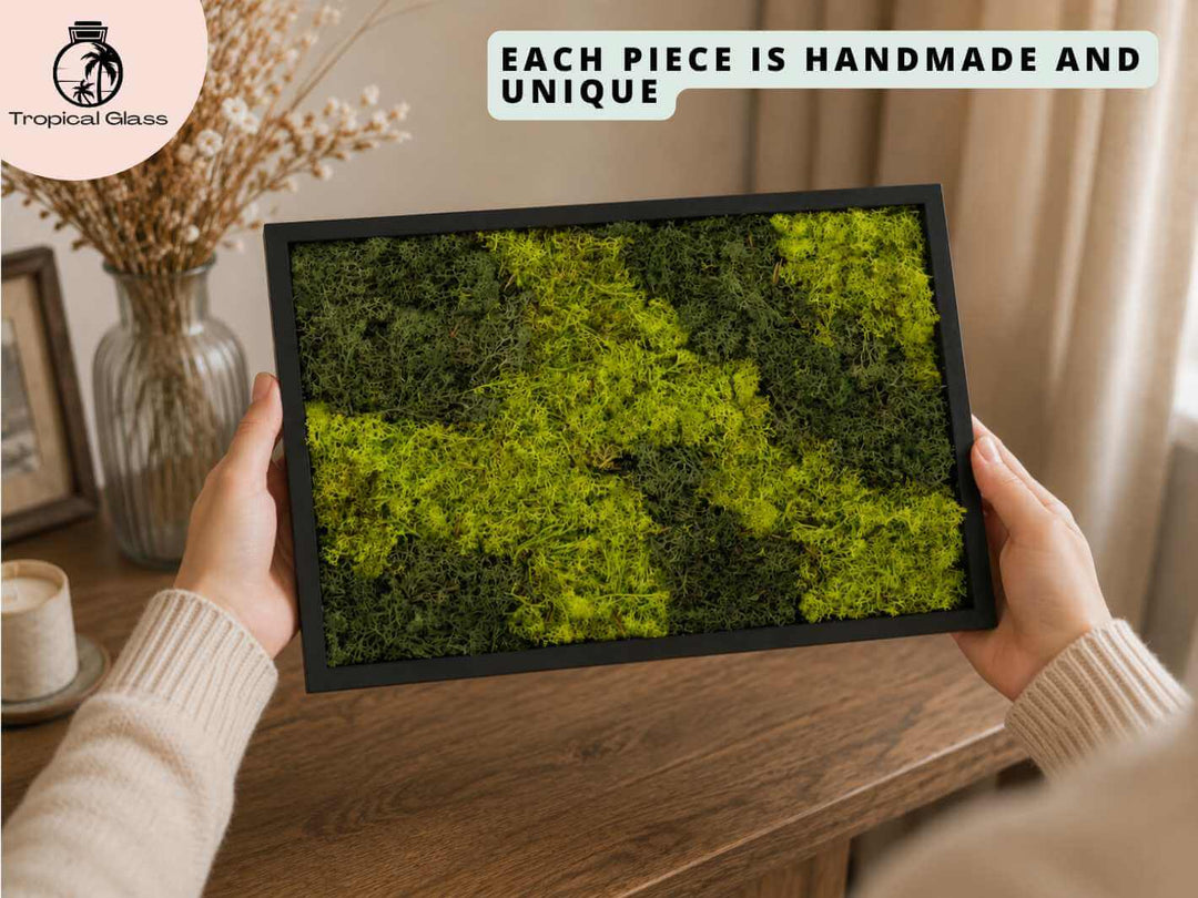 Person holding and admiring a handmade preserved moss frame, showing the natural green texture and wooden frame detail