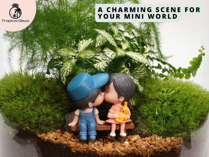 Mini couple figurine sitting on bench inside glass terrarium, decorative miniature setup with greenery