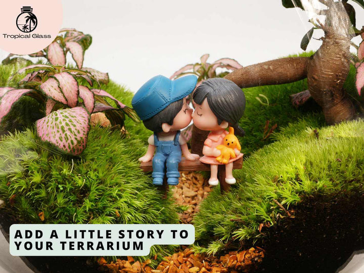 Mini couple figurine on bench placed inside a moss terrarium, lifestyle scene with plants and natural elements