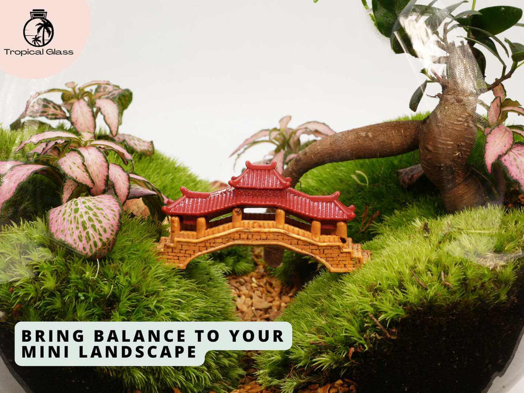 Mini pagoda bridge placed inside a terrarium with moss and plants