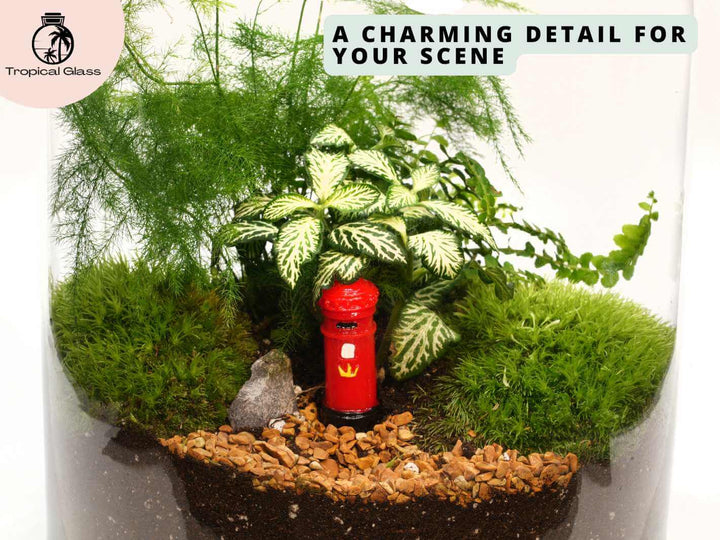 Mini red British post box figurine placed in a terrarium scene with moss and plants