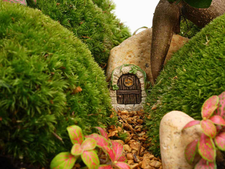 Back view of a stone fairy door terrarium accessory with green details