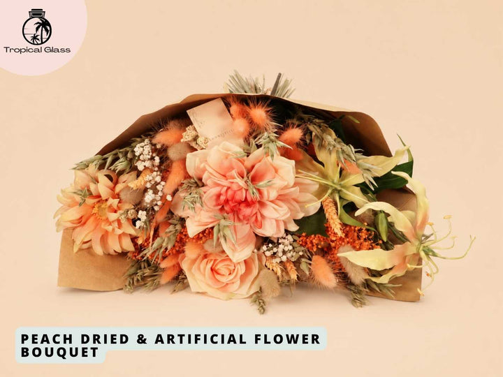 A beautifully arranged bouquet featuring soft peach-colored flowers, including large blooms and delicate dried elements, wrapped in natural brown paper. The bouquet showcases a mix of textures and colors, perfect for gifting or decoration.
