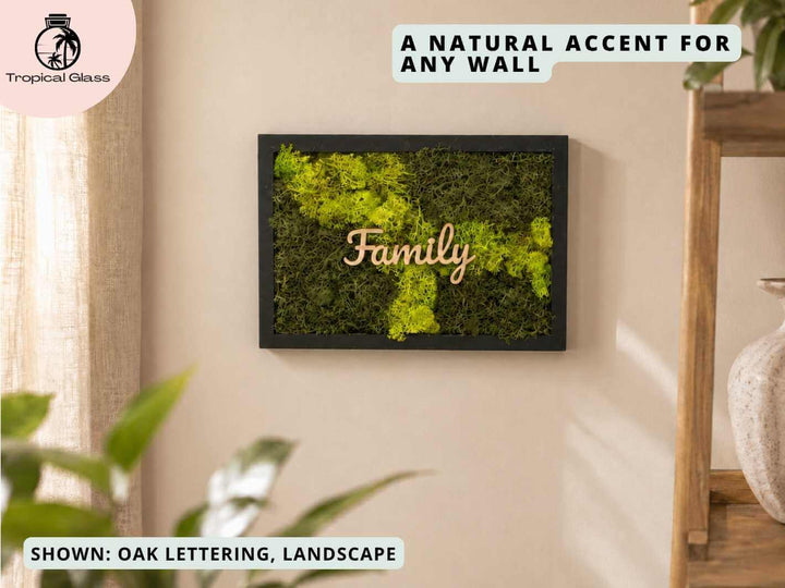 A framed piece of moss wall art features vibrant green moss arranged in a rectangular design, with the word Family crafted from oak lettering in the center.