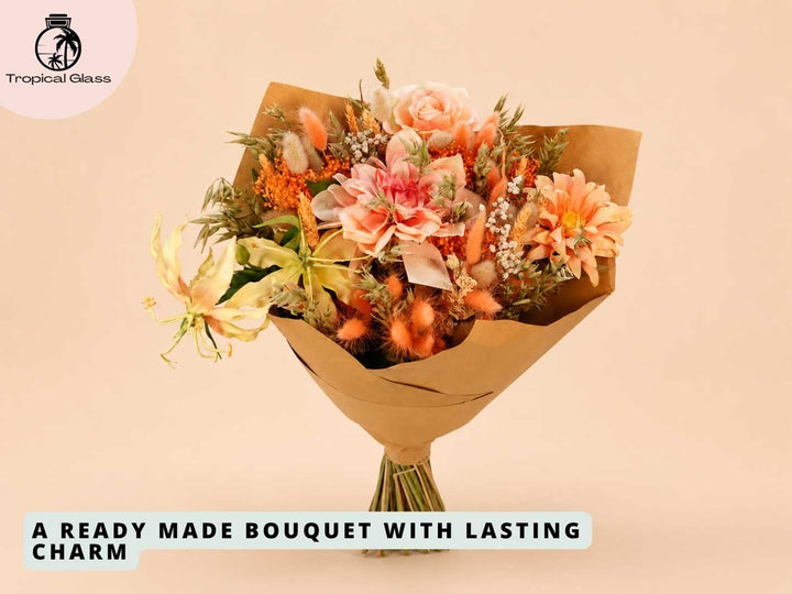 A beautifully arranged bouquet featuring soft peach and orange flowers, including roses and daisies, accented with dried elements. Wrapped in natural kraft paper, this bouquet exudes charm and elegance, perfect for gifting.
