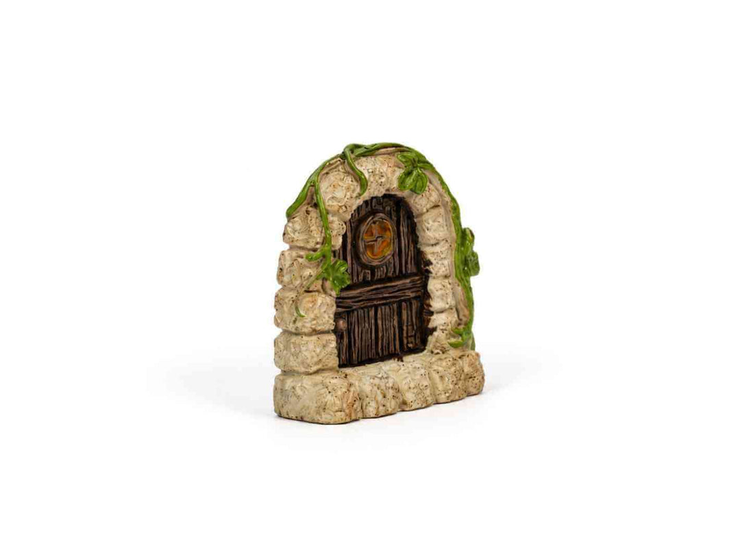 Miniature fairy door hidden in green moss inside a terrarium