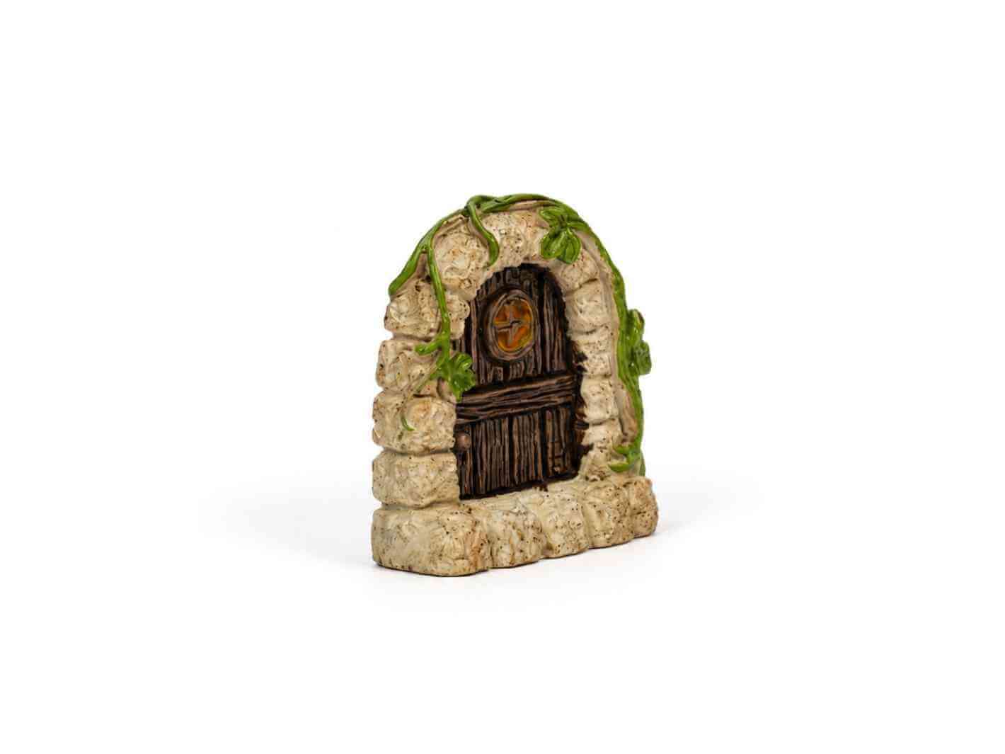 Miniature fairy door hidden in green moss inside a terrarium