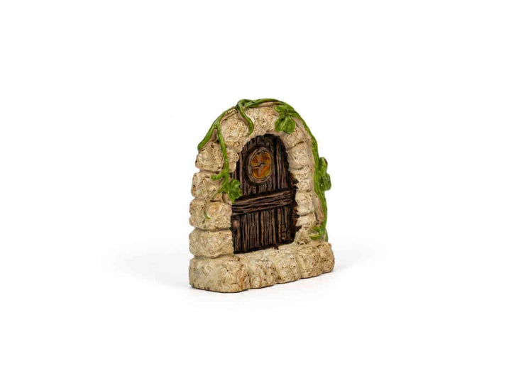 Miniature fairy door hidden in green moss inside a terrarium