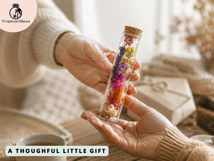 Dried flower glass bottle being gifted from one hand to another as a thoughtful floral present
