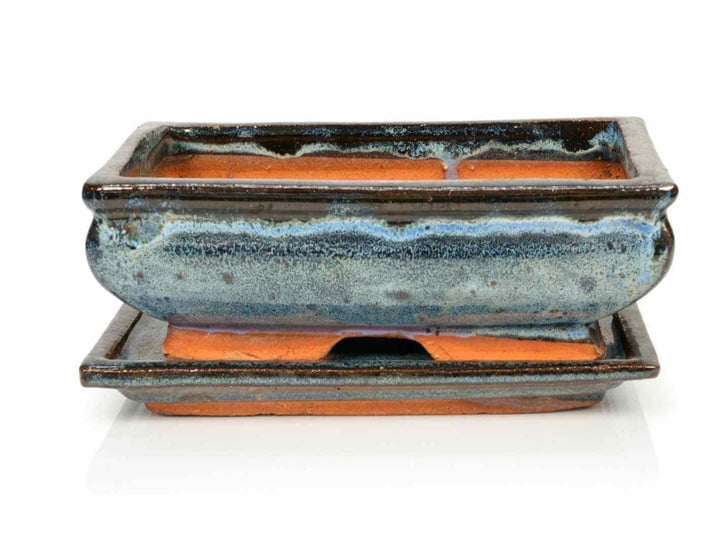 A decorative ceramic pot with a saucer, featuring a glossy dark blue and brown glaze. The pot is rectangular with a sleek design, resting on a matching saucer.