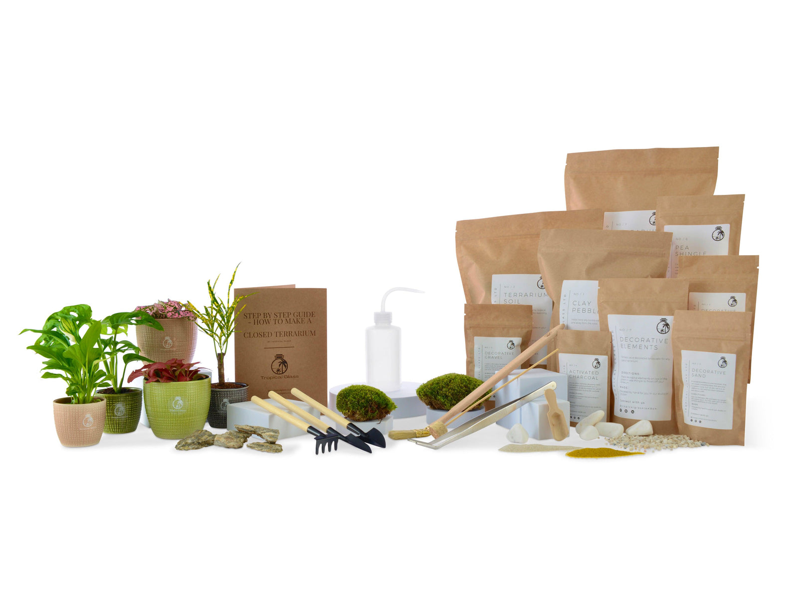 A variety of terrarium supplies is displayed, including small potted plants, bags of soil and decorative elements, gardening tools, and a spray bottle.