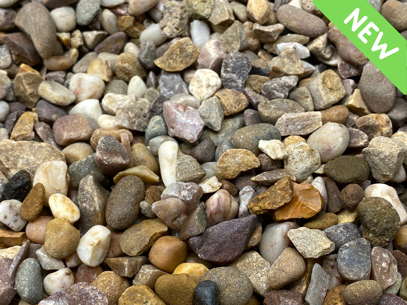 A close-up view of a variety of polished river pebbles in different colors and sizes, showcasing earthy tones of brown, gray, and cream. A bright green label in the corner reads NEW, indicating the freshness of the product.