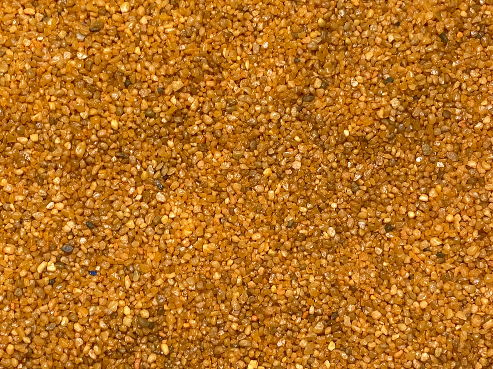 Close-up view of granular orange sand, showcasing a rich texture with small, irregularly shaped grains. The vibrant orange color adds a striking visual appeal, making it suitable for terrariums, aquariums, and various craft projects.