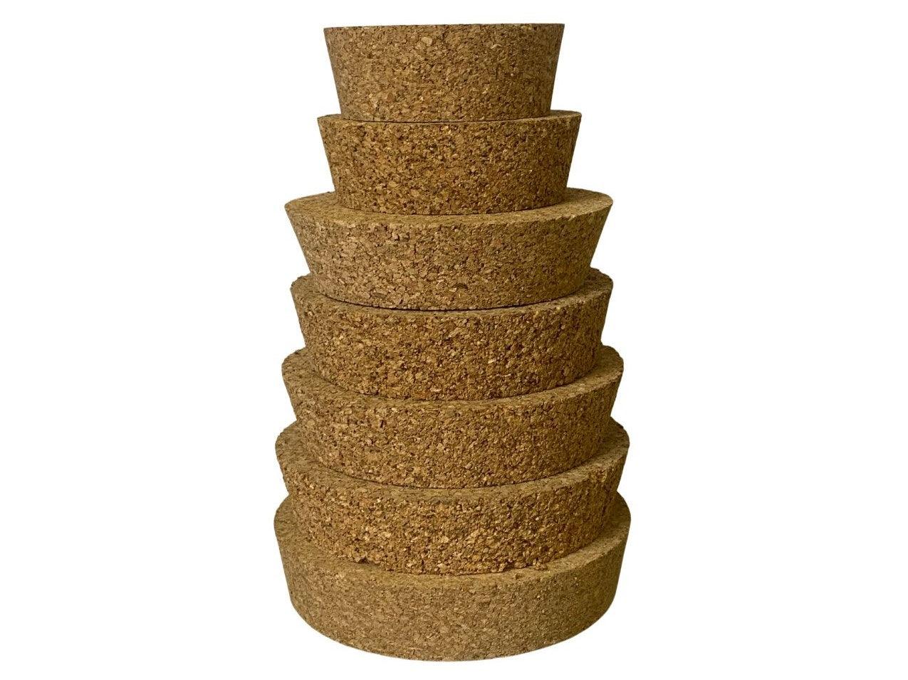 A stack of tapered cork lids in various sizes, showcasing their natural texture and circular shape. These cork stoppers are ideal for sealing containers like terrariums and jars, providing a rustic and eco-friendly closure option.