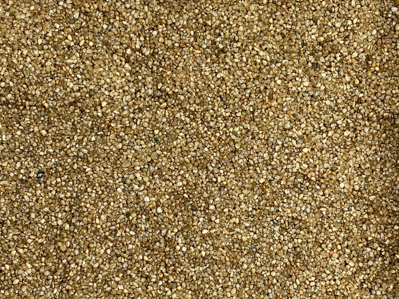 A close-up view of fine gold quartz sand, showcasing its small, granulated particles that range in color from light to dark golden hues.