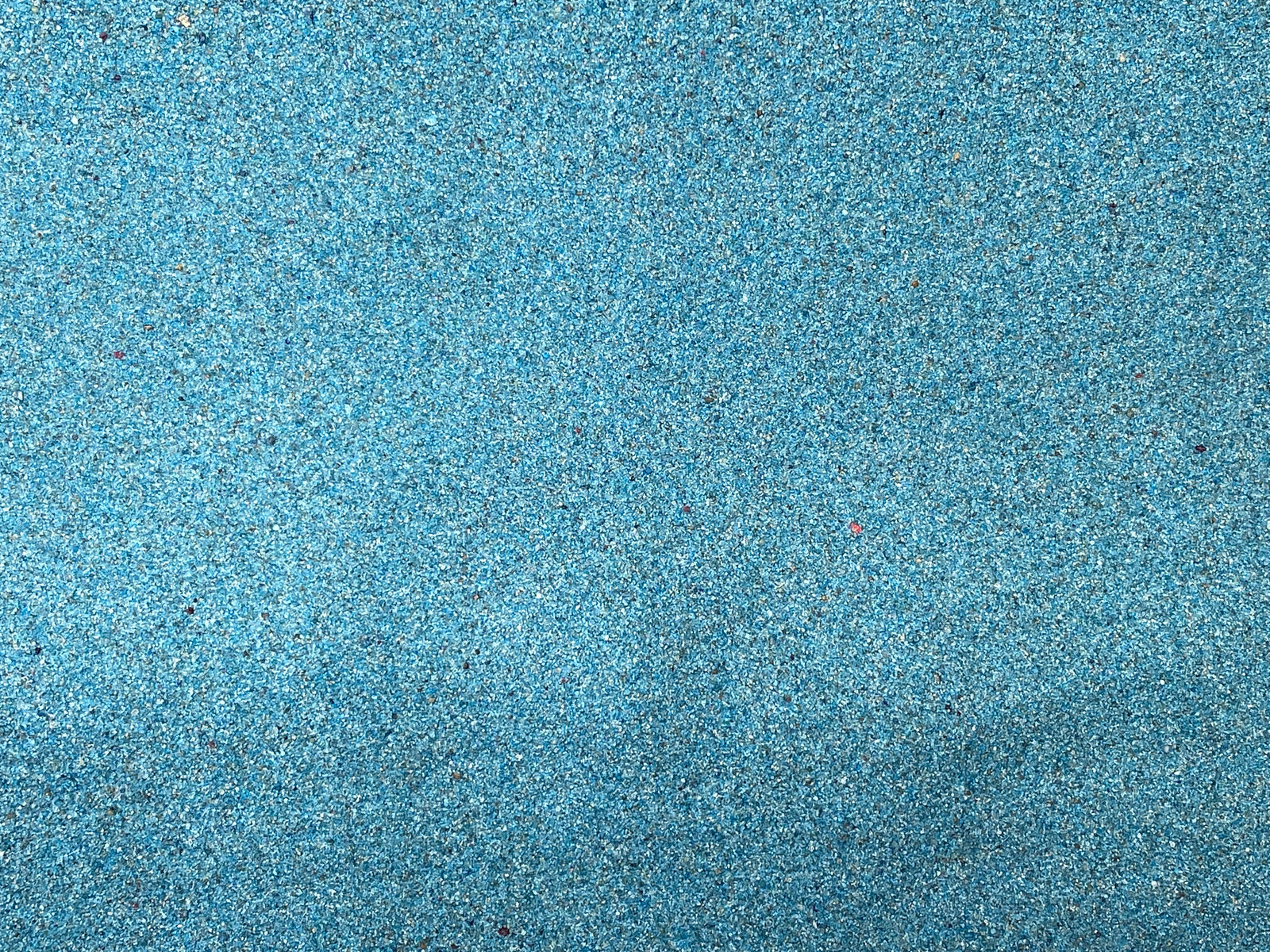 Close-up view of shimmering premium blue decorative sand, featuring a fine texture with a sparkling finish. The vibrant blue color adds a bright and eye-catching element, making it ideal for various decorative projects and terrariums.