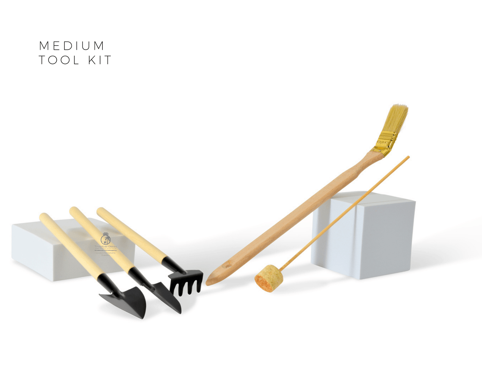 A medium garden tool kit featuring five essential tools: a shovel, rake, spade, brush, and cork tamper, each with a wooden handle and black metal heads.